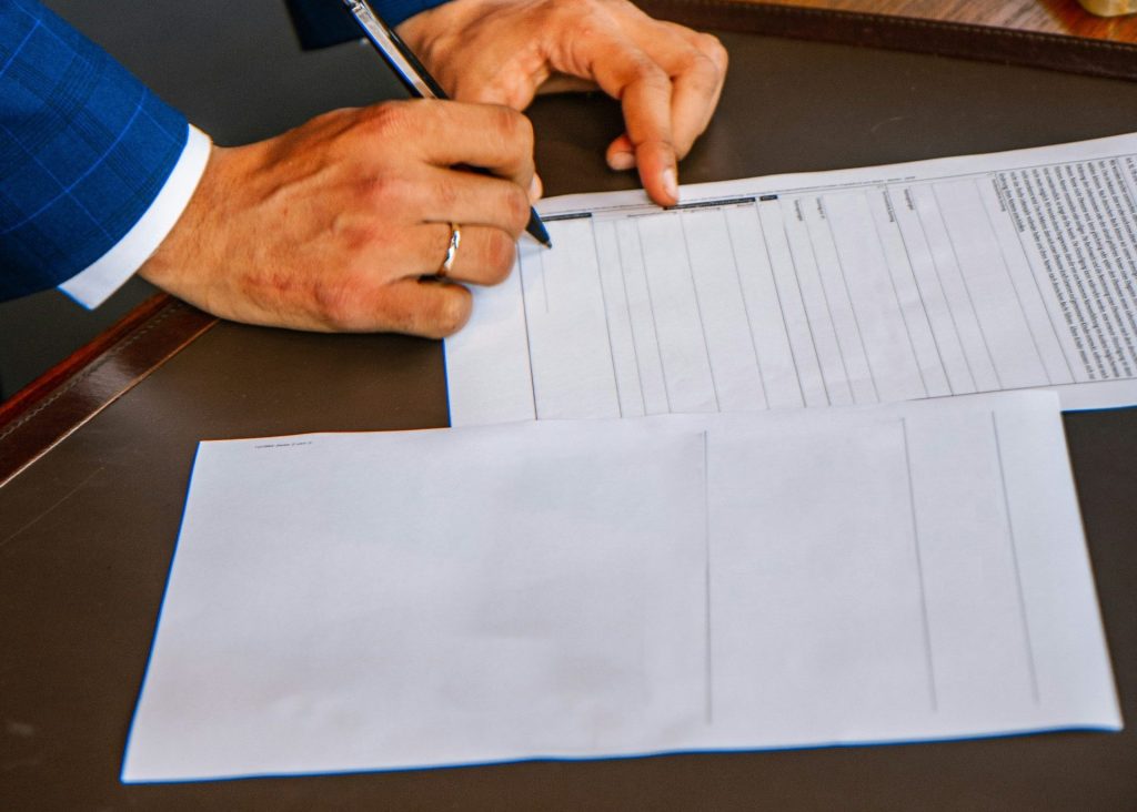person writing on white form paper